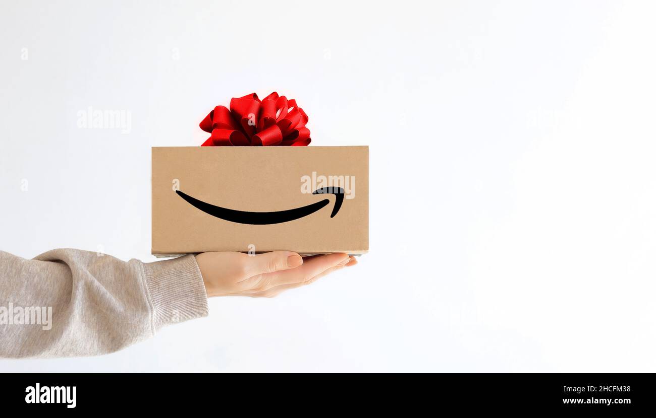 Express delivery Amazon. A young woman in sweatshirt holds a cardboard boxes with a red bow. Online shopping Sale Stock Photo