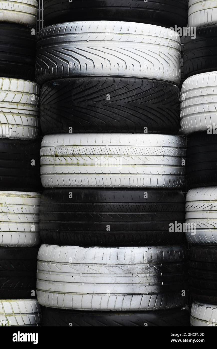Stacks of black and white old tires, forming a checkered pattern. Portrait orientation. Stock Photo