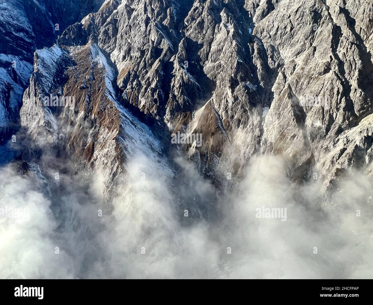 Aerial view of mountain peaks covered in snow coming out through the ...