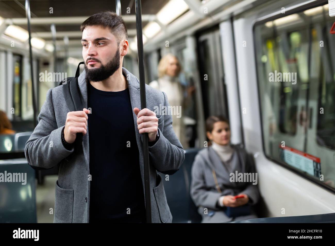 Guy holding on handrails in city bus Stock Photo - Alamy