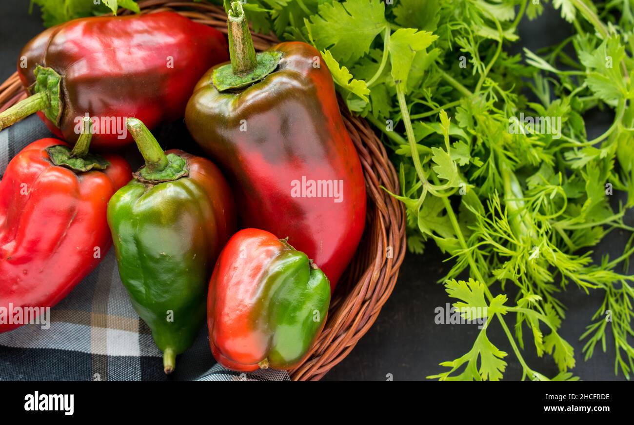 Some fresh red chili pepper in a basket with fresh coriander on a black wooden table Stock Photo