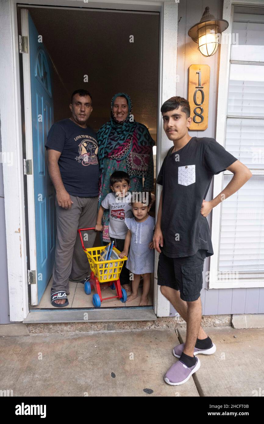Austin Texas USA, October 2021: Members of an Afghan family pose at the door of their new home in an apartment complex in north Austin. Refugees fleeing turmoil in Afghanistan continue to be resettled in Texas with many single men and large families with children moving into apartments across Austin. Faith-based and other non-profit groups have stepped up to help coordinate efforts in furnishing homes for hundreds of refugees. ©Bob Daemmrich Stock Photo