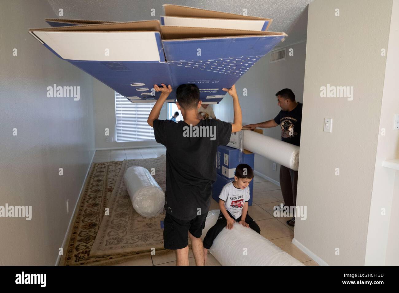 Austin Texas USA, October 2021: Members of an Afghan family move donated furniture into their new home in an apartment complex near downtown. Refugees fleeing turmoil in Afghanistan continue to be resettled in Texas with many single men and large families with children moving into apartments across Austin. Faith-based and other non-profit groups have stepped up to help coordinate efforts in furnishing homes for hundreds of refugees. ©Bob Daemmrich Stock Photo
