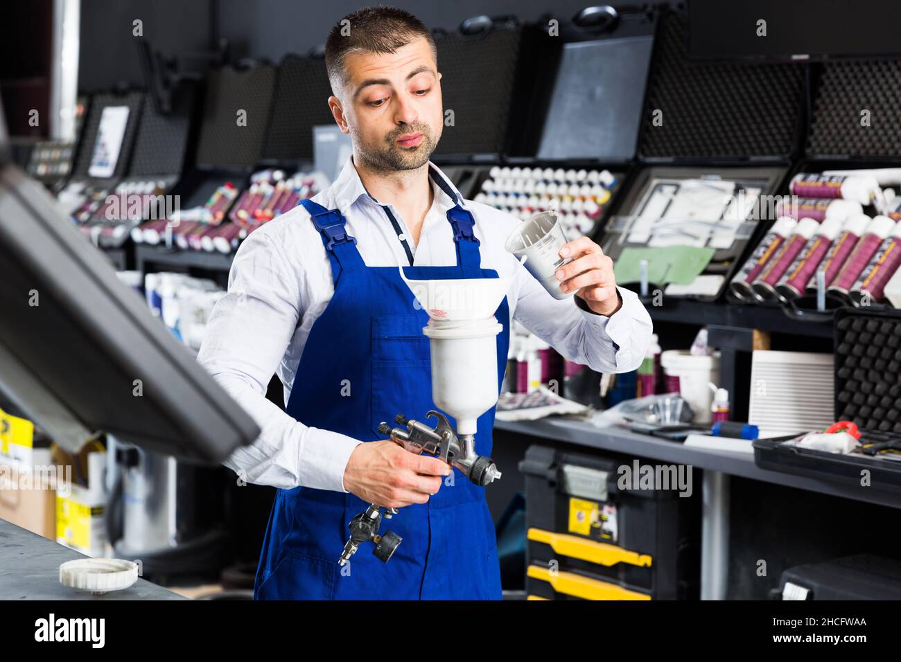 Mechanic pouring paints in paintspray gun Stock Photo Alamy