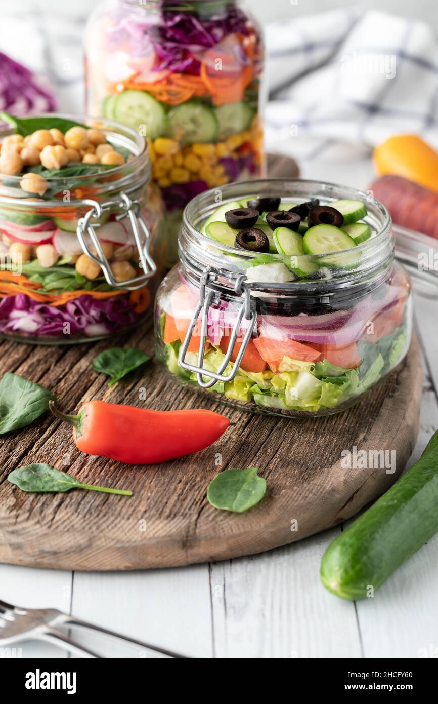 Jars filled with freshly made salad on a rustic wooden board. Stock Photo