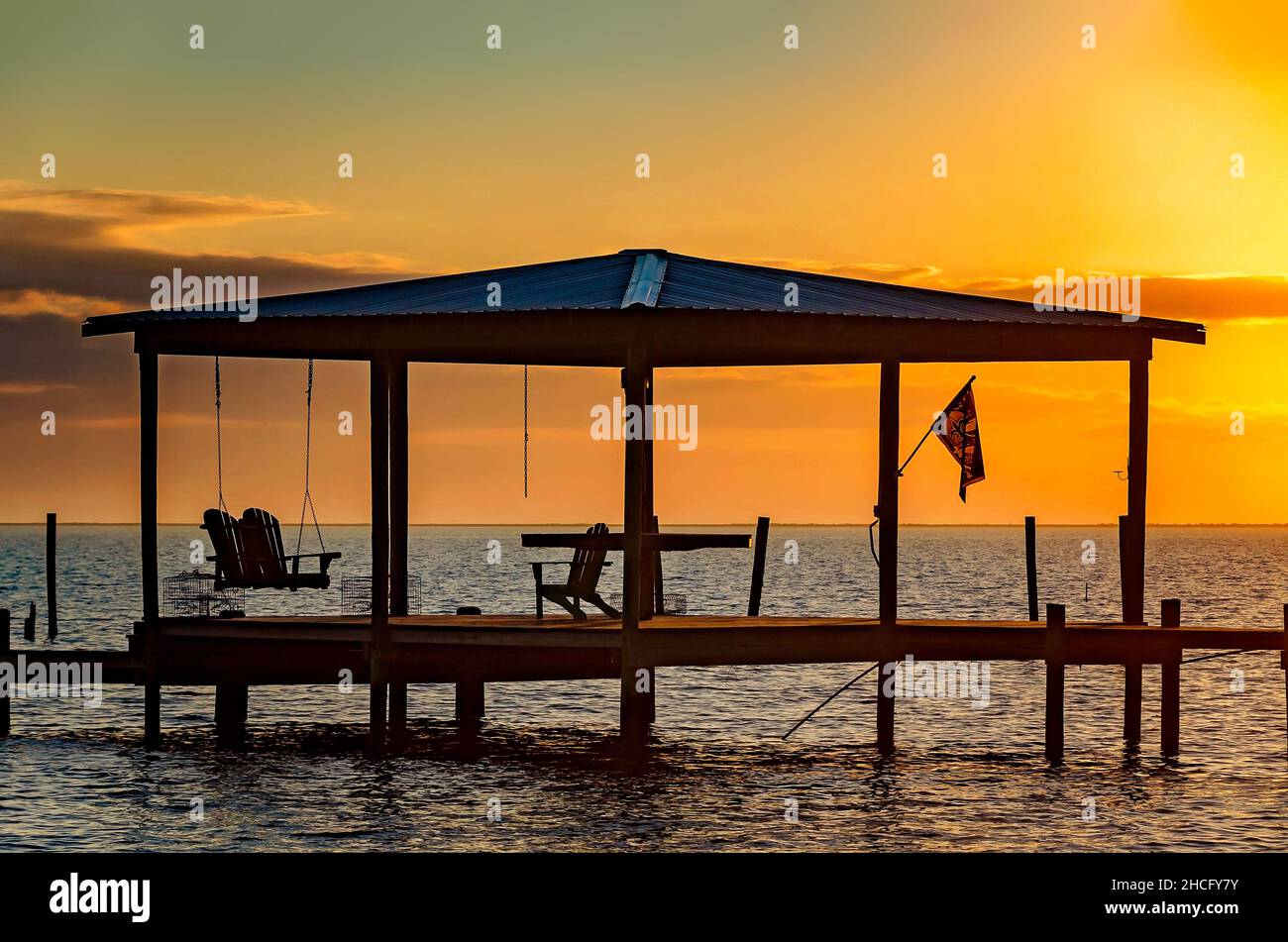 The sun sets on a boat dock on Coden Beach, Dec. 27, 2021, in Coden