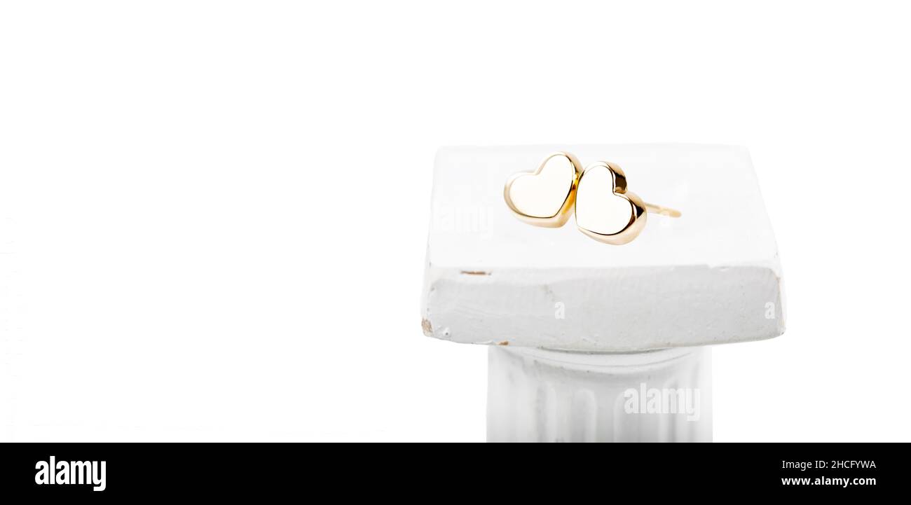 Heart-shaped gold stud earrings on a white background. Stock Photo