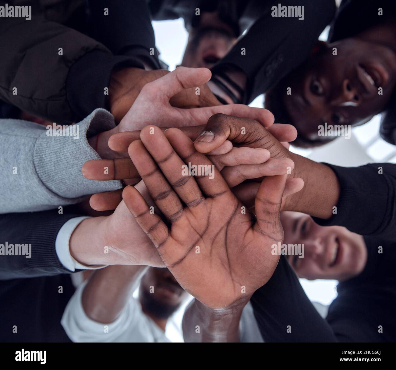 bottom view. a group of diverse young people joining their hands ...