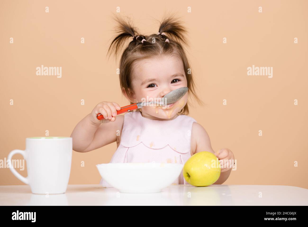 Babies eating, healthy food for a baby. Babys first meal. The child eats on his own with a spoon and plate. Stock Photo