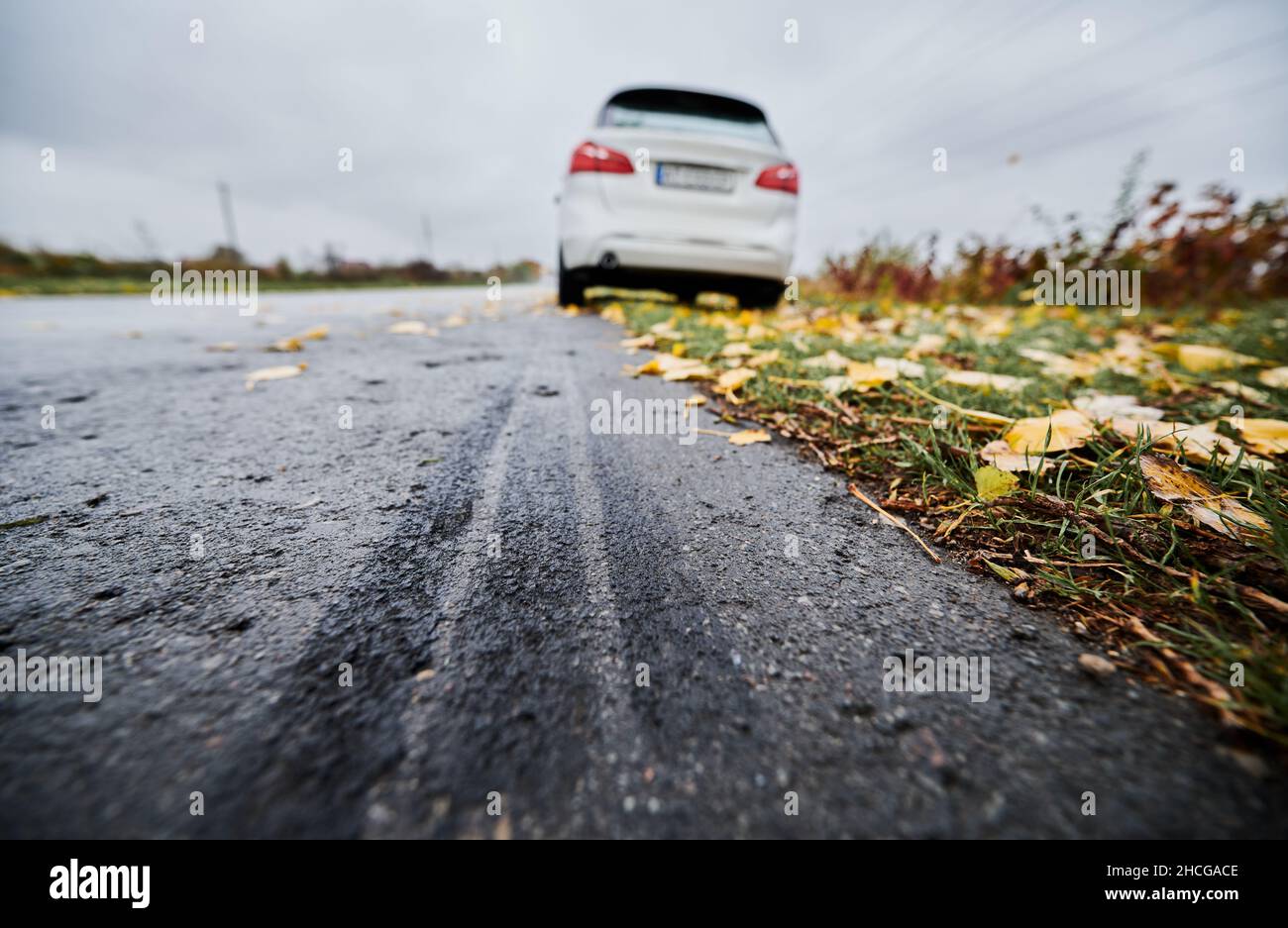 Tire mark on the asphalt road. Stopped white car with punctured car