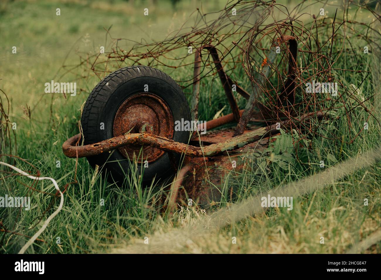 A closeup of a rusty and abandoned cart on a wheel turned upside down in the countryside Stock Photo