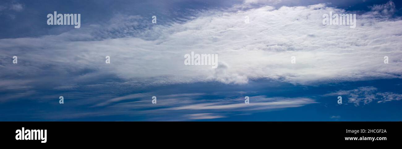 Blue sky with white clouds illuminated by the bright sun. Stock Photo