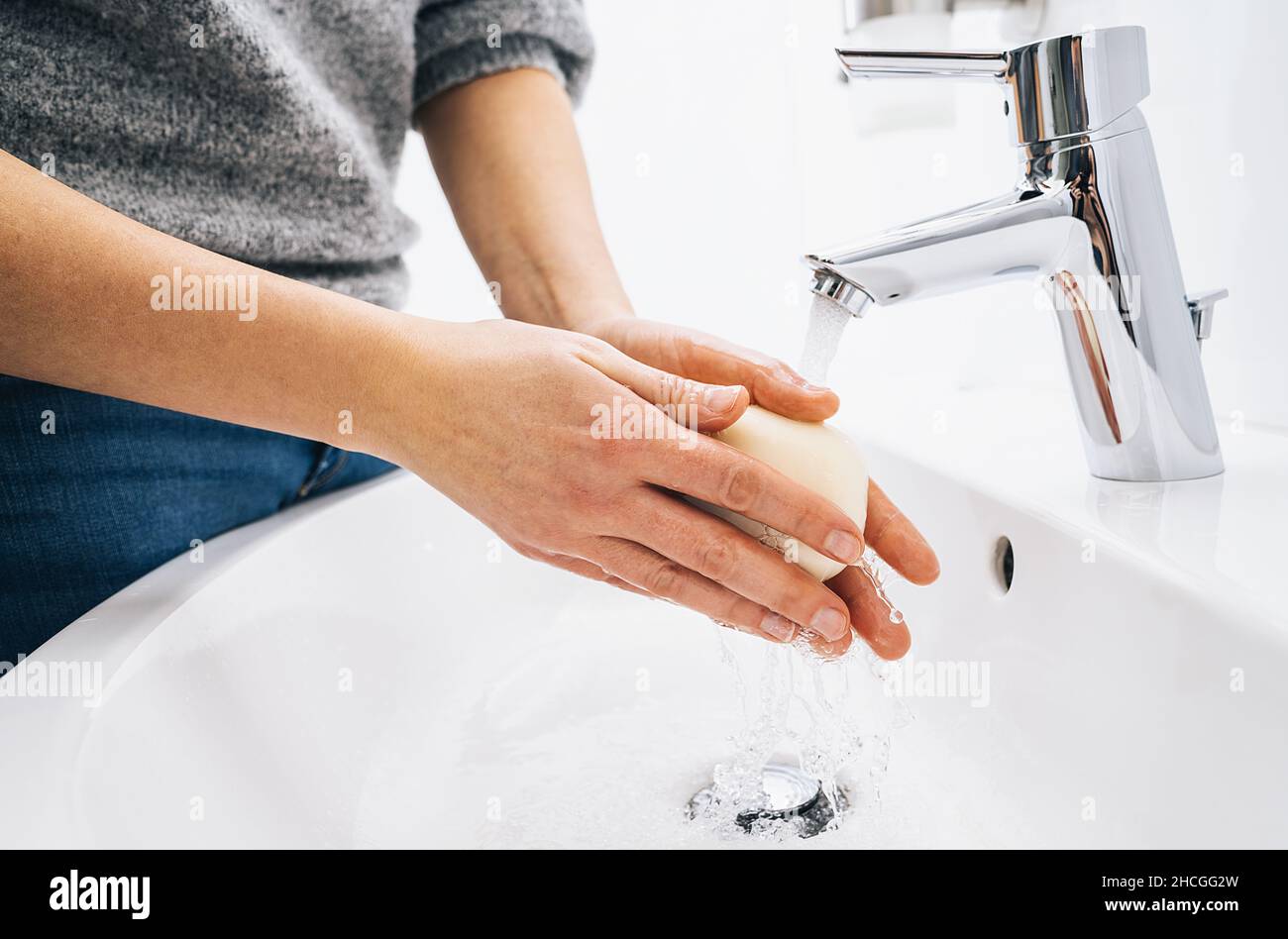 Washing hands with soap and hot water at home bathroom sink woman ...