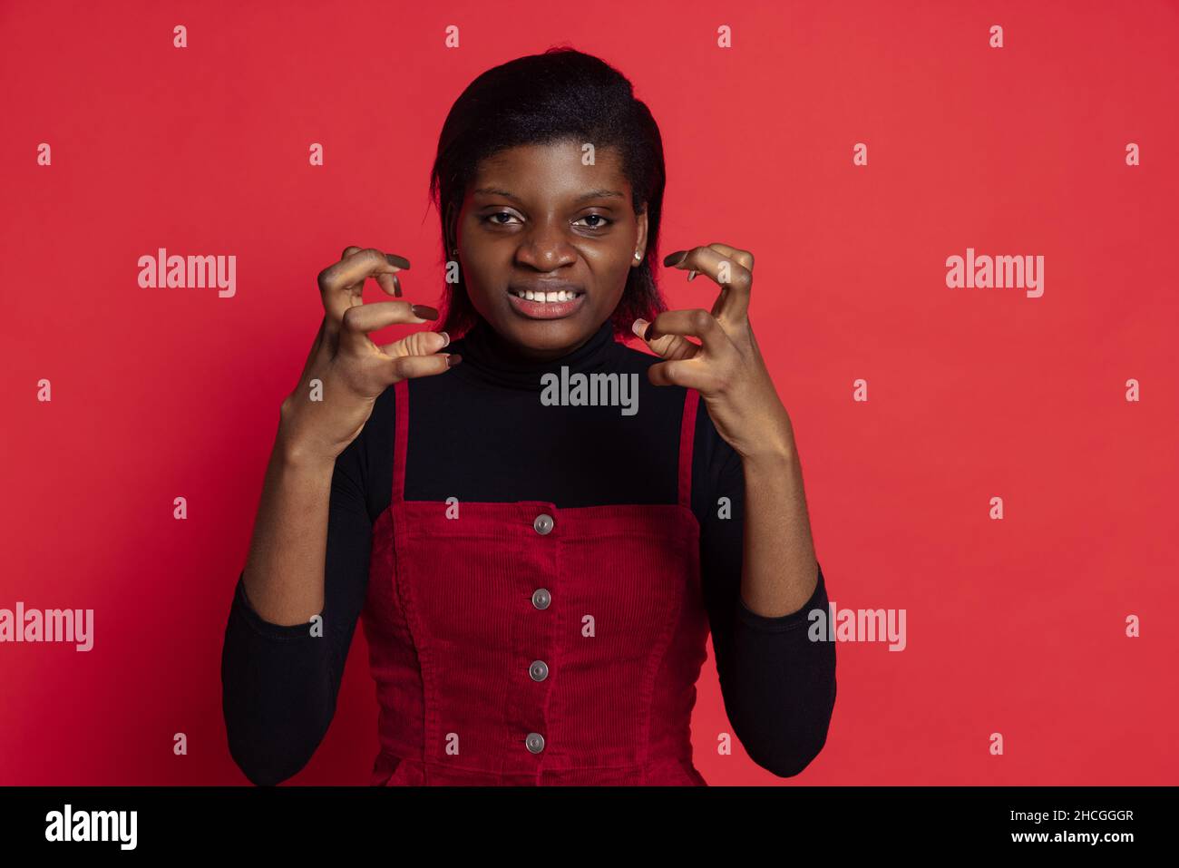 Angry young dark skinned girl angries isolated on dark red studio ...