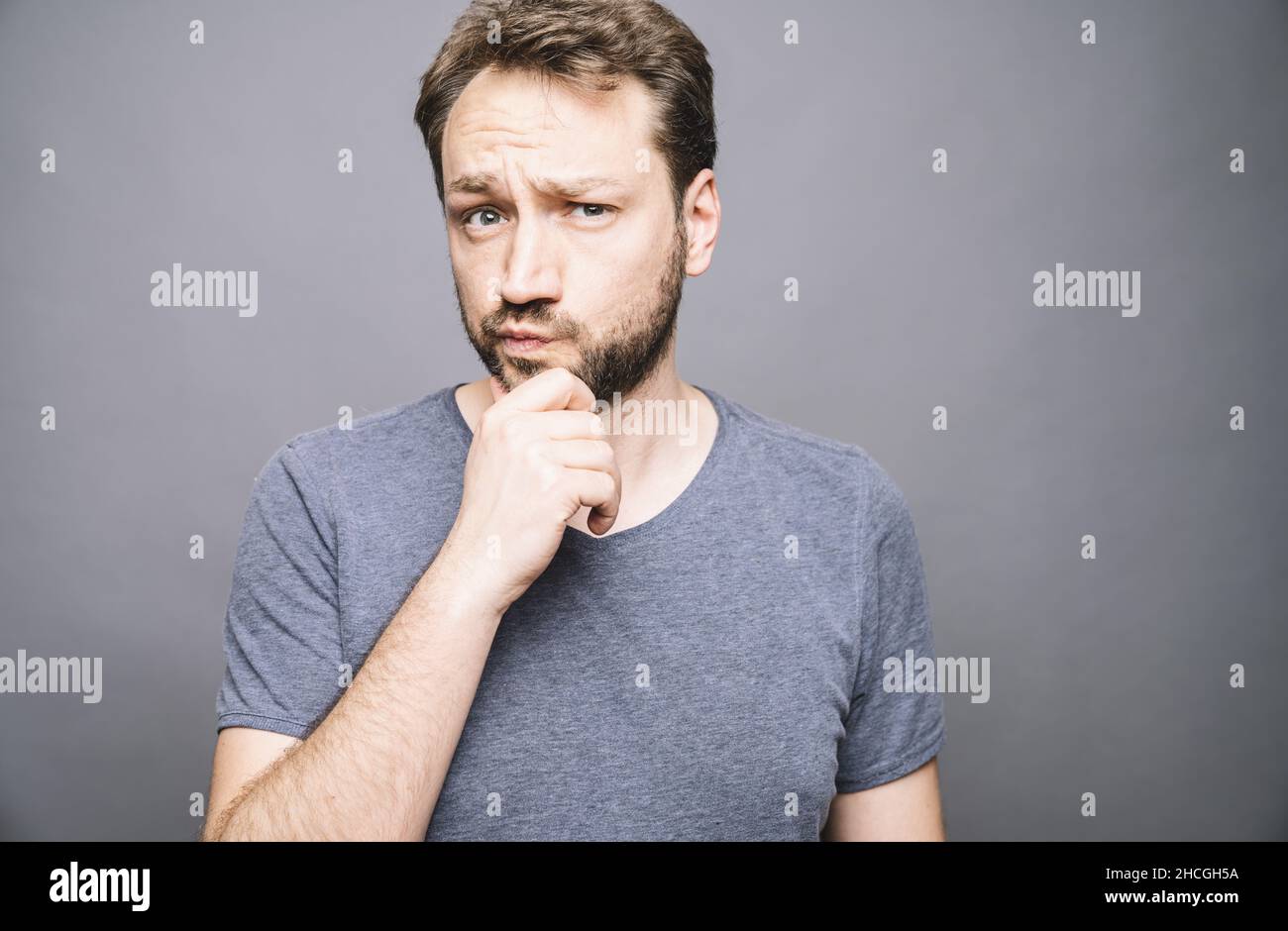 thoughtful man who looks away touching his chin and weighs the pluses and minuses of the offer Stock Photo