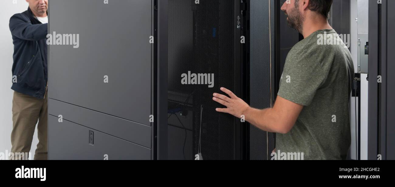 Technicians team updating hardware inspecting system performance in super computer server room or cryptocurrency mining farm. Stock Photo