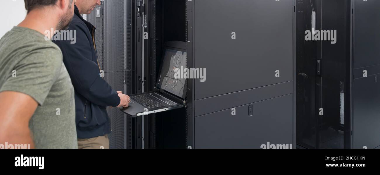 Technicians team updating hardware inspecting system performance in super computer server room or cryptocurrency mining farm. Stock Photo