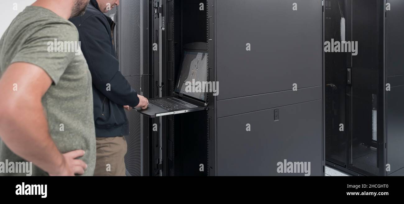 Technicians team updating hardware inspecting system performance in super computer server room or cryptocurrency mining farm. Stock Photo