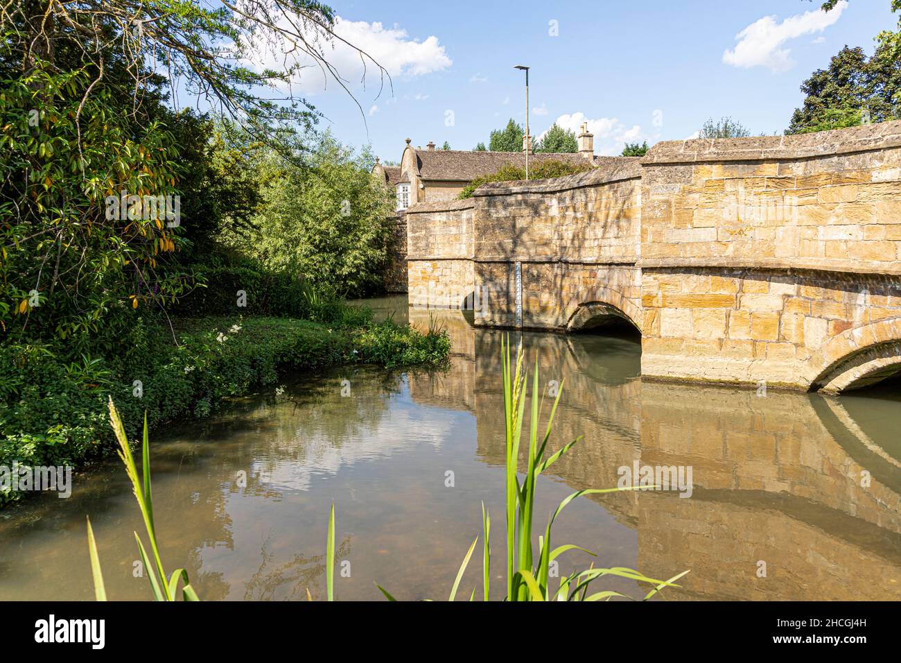 The River Windrush flowing under the old stone bridge in the Cotswold town of Burford, Oxfordshire UK Stock Photo