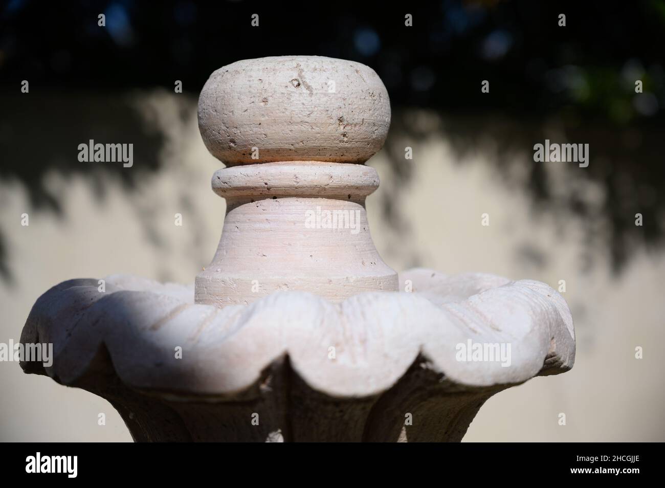 Shallow focus shot of a garden fountain made of concrete on a tree background Stock Photo