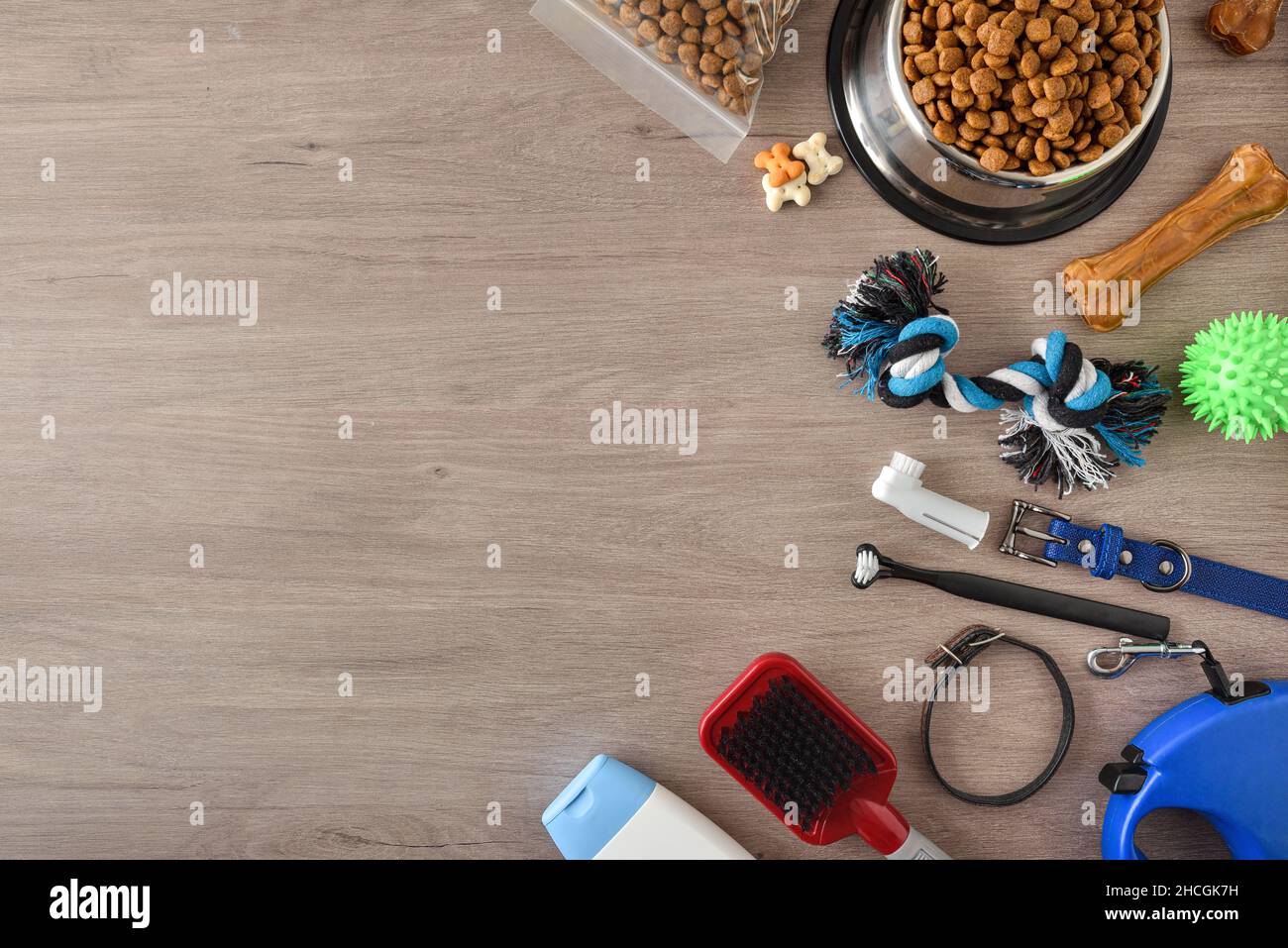 Food and accessories for walk, play and body care for the dog on wooden table. Top view. Horizontal composition. Stock Photo