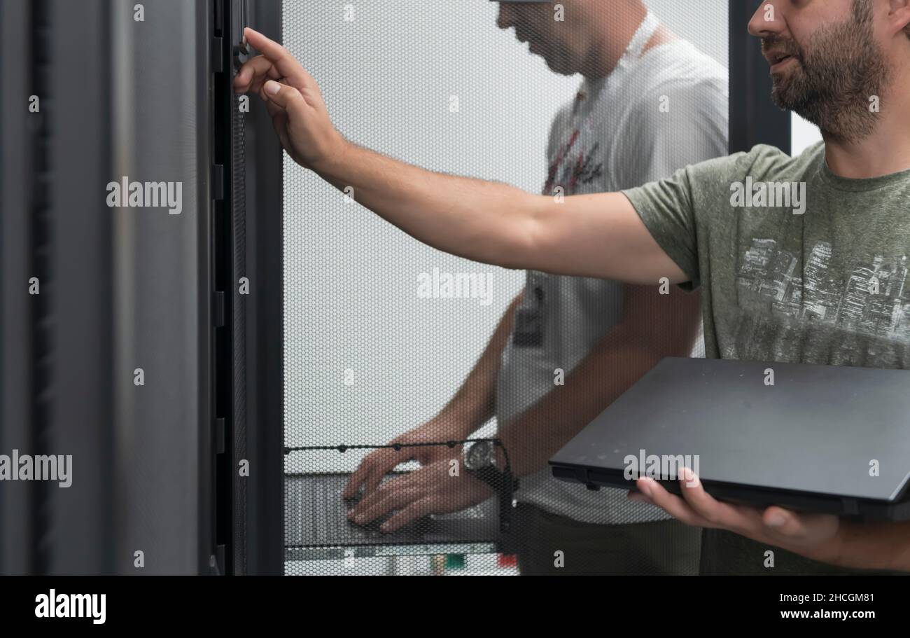 Technicians team updating hardware inspecting system performance in super computer server room or cryptocurrency mining farm. Stock Photo