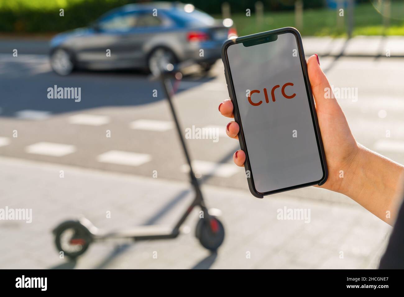 Woman hand holding iphone Xs with logo of CIRC app displayed on a smartphone to rent a e-Scooter. Circ is a rental electric scooter company. Quick Stock Photo