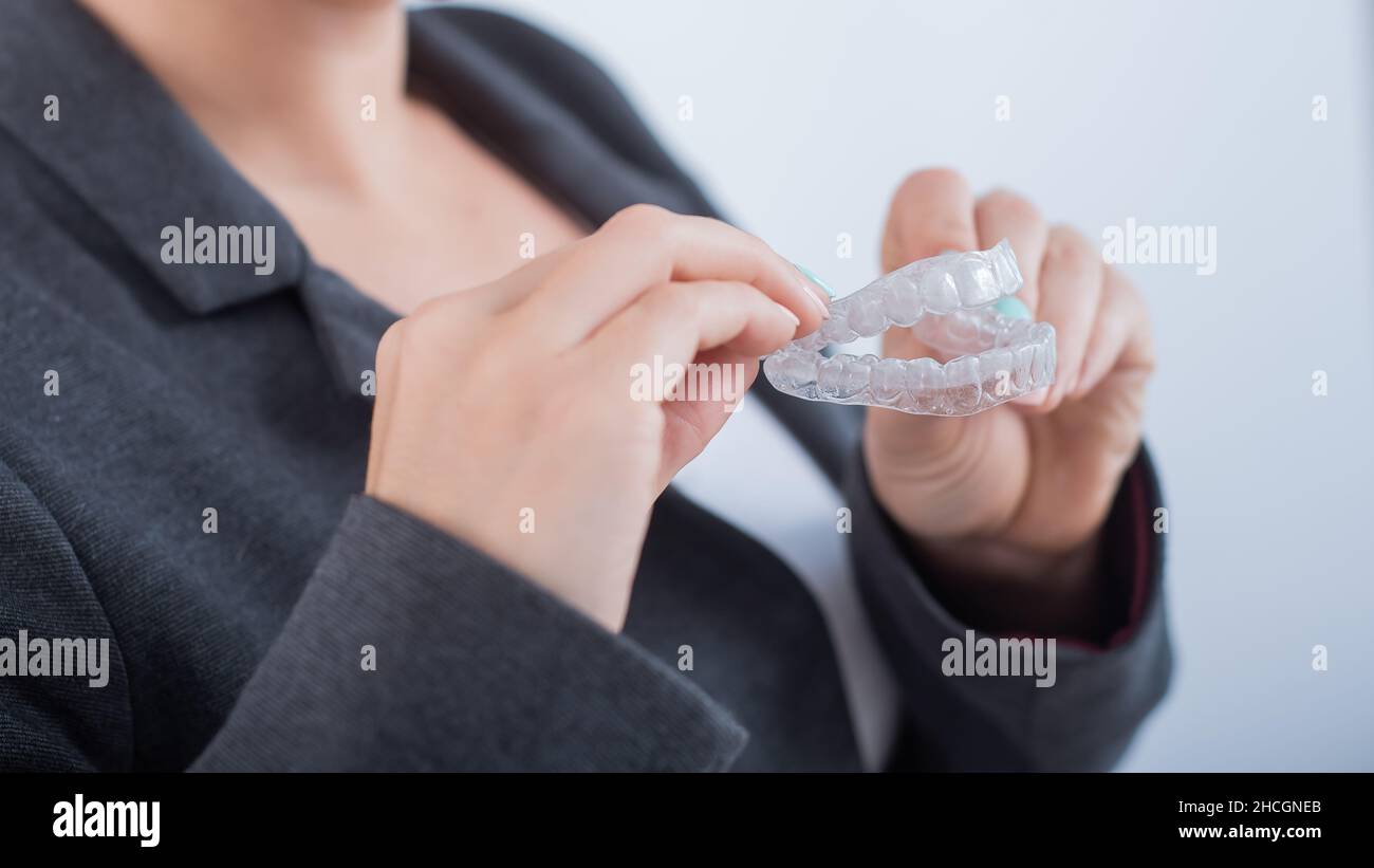 A woman is holding a transparent plastic mouth guard. Orthodontist's