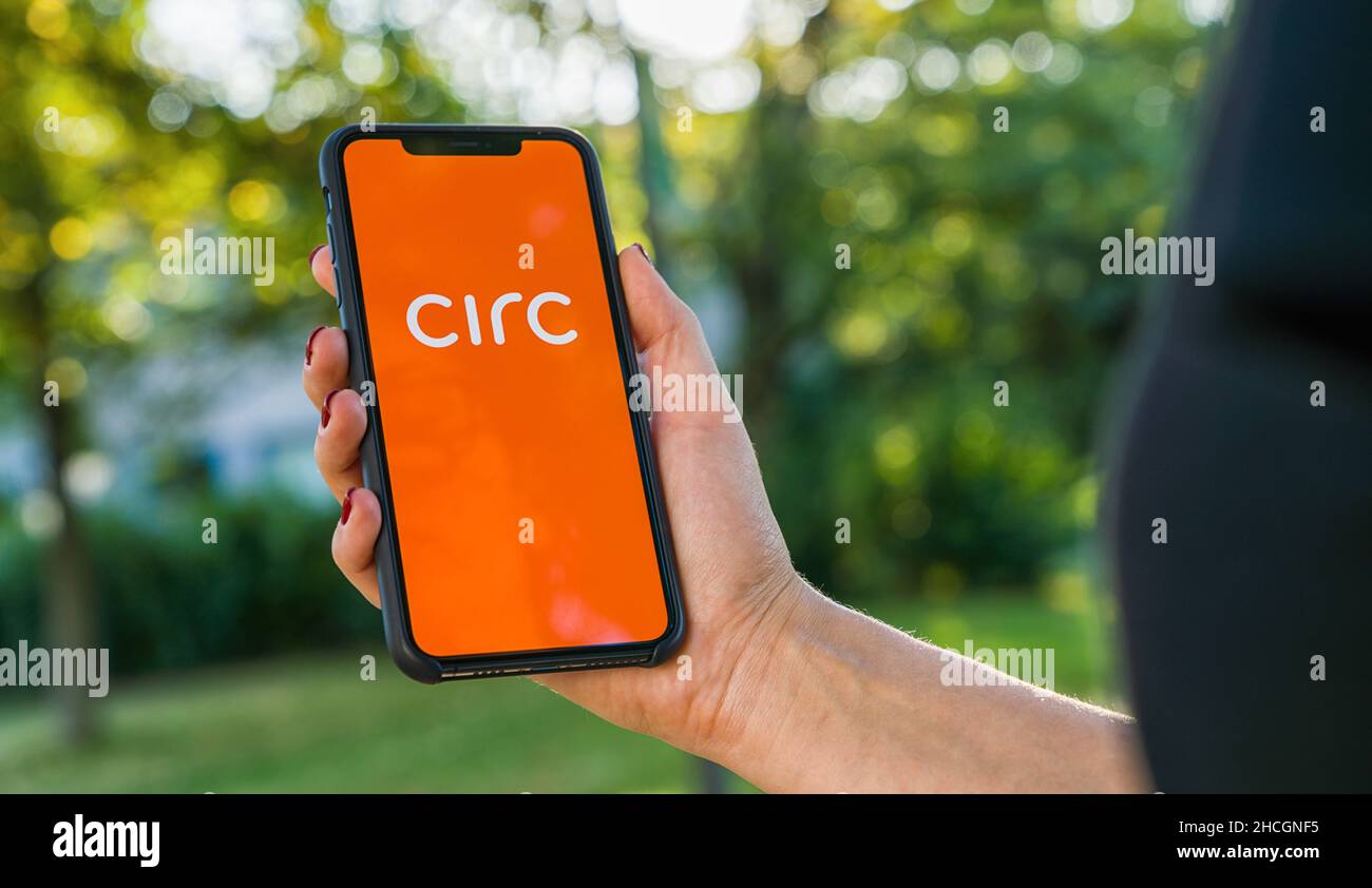 Woman hand holding iphone Xs with logo of CIRC app displayed on a smartphone to rent a e-Scooter. Circ is a rental electric scooter company. Quick and Stock Photo