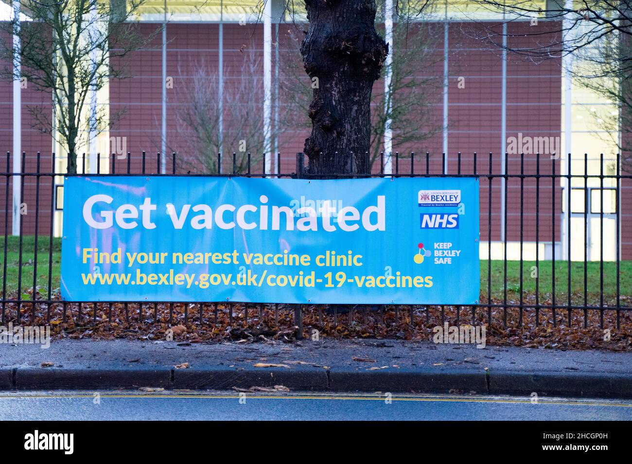 Get Vaccinated banner tied to railings out side a public library at road side Bexley Council England UK Stock Photo