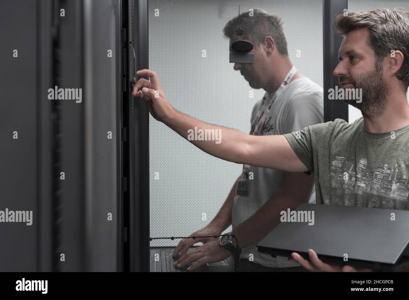 Technicians team updating hardware inspecting system performance in super computer server room or cryptocurrency mining farm. Stock Photo