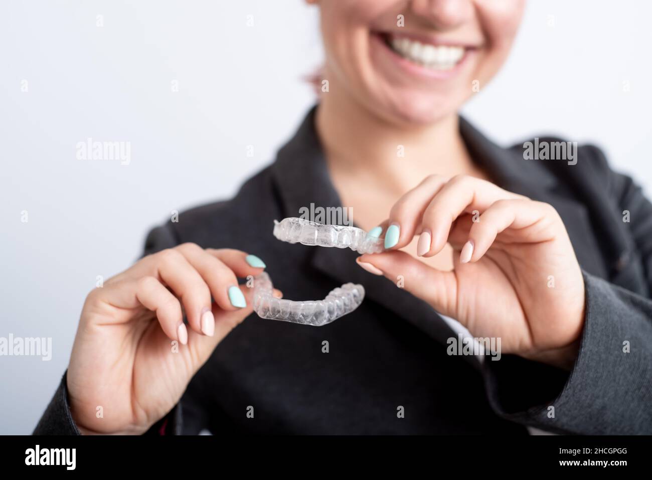 A woman is holding a transparent plastic mouth guard. Orthodontist's