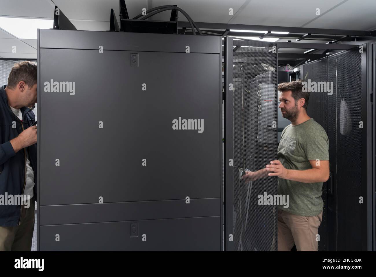 Technicians team updating hardware inspecting system performance in super computer server room or cryptocurrency mining farm. Stock Photo