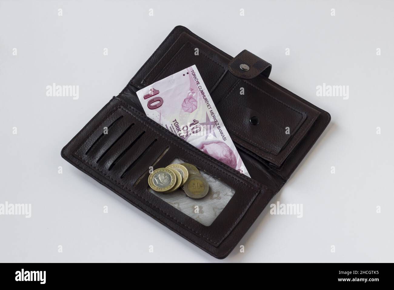 Only Turkish Ten Liras and coins are in brown leather women's wallet at white background. Stock Photo