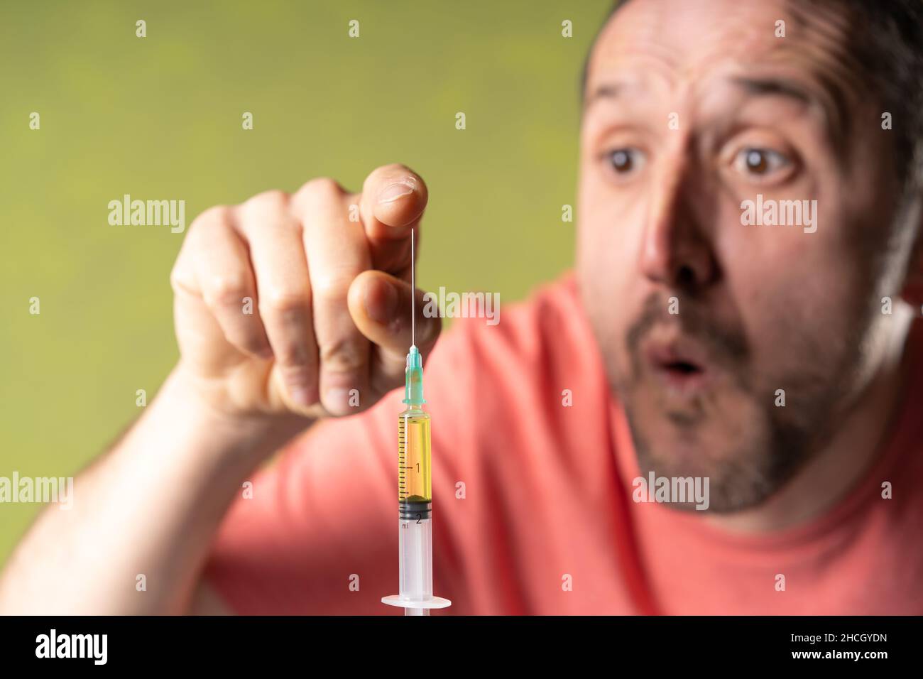 Man touches doubtfully  the anti covid vaccine needle. Stock Photo