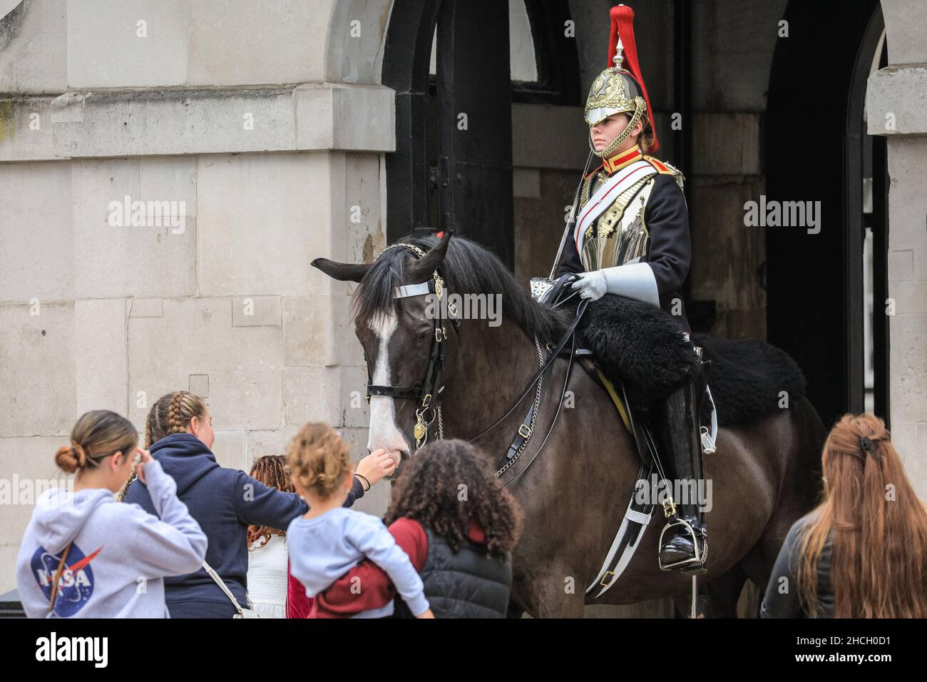 Tourists around a young female soldier, mounted on horseback, Blues and Royals member of the Household Cavalry at Horse Guards Parade, London, UK Stock Photo