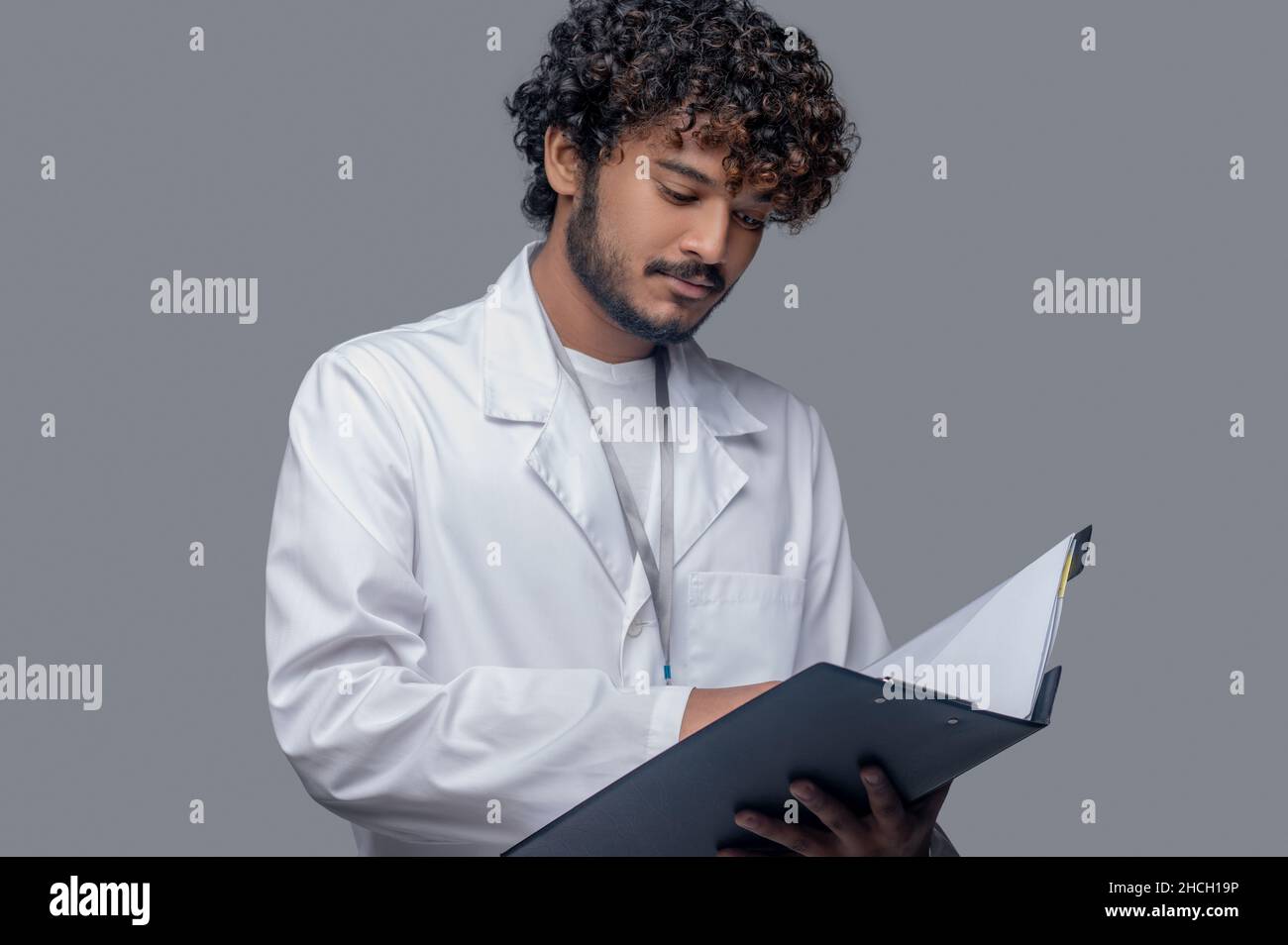 Concentrated physician holding documents in his hands Stock Photo