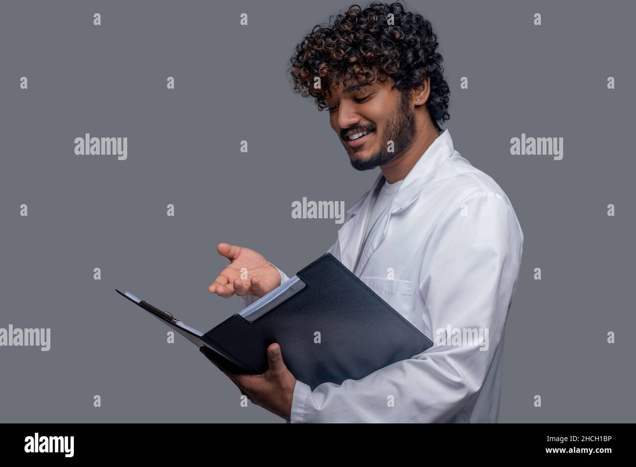 Smiling doctor scrutinizing documents in his hands Stock Photo
