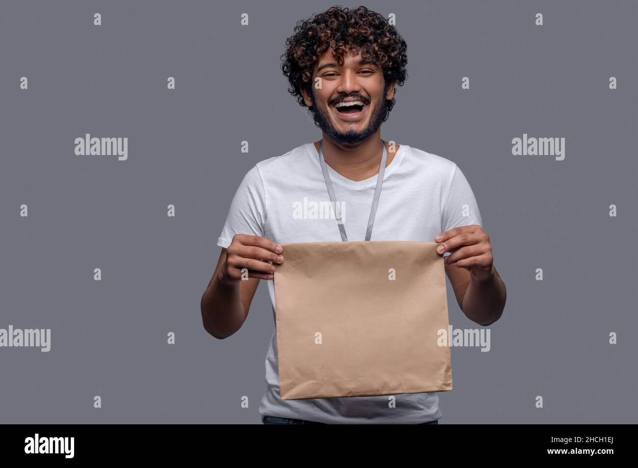 High-spirited deliveryman holding the package with both hands before him Stock Photo