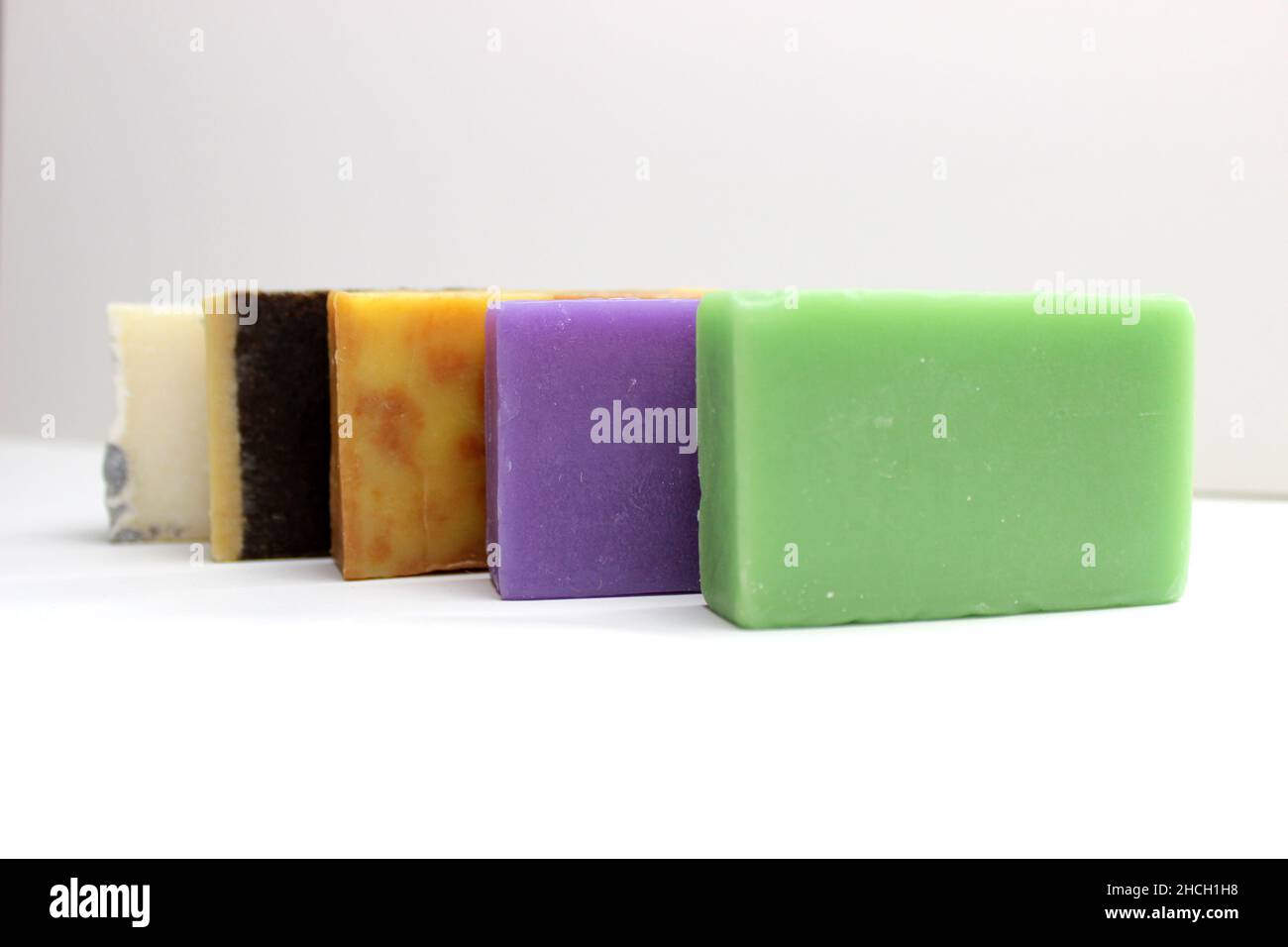 top view of various handcrafted soap with different ingredients in row on white surface Stock Photo