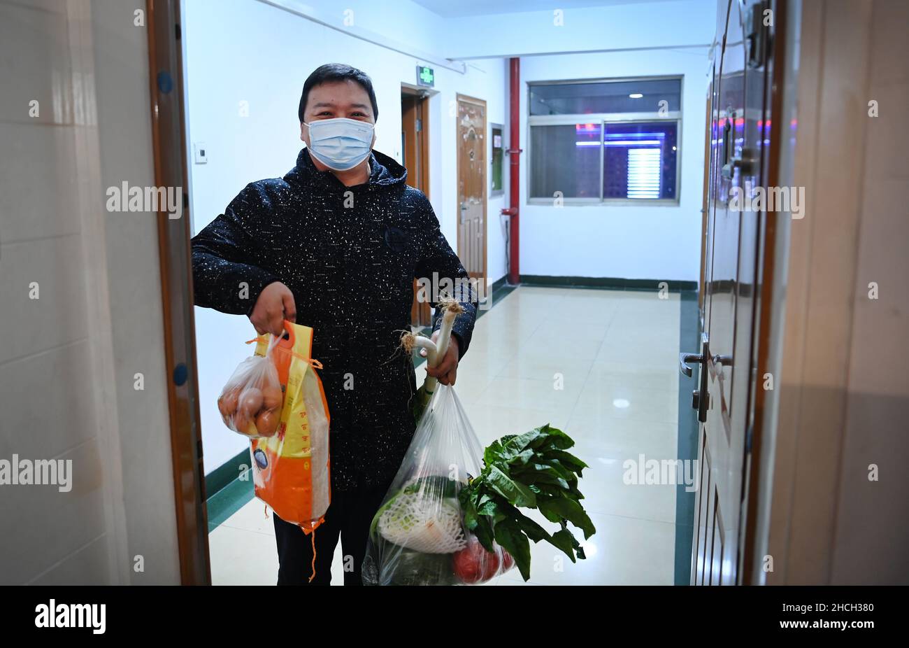 Xi'an, China's Shaanxi Province. 29th Dec, 2021. A community worker delivers daily necessities to a household under closed-off management in Xi'an, capital of northwest China's Shaanxi Province, Dec. 29, 2021. Authorities in Xi'an have upgraded epidemic control and prevention measures starting Monday, ordering all residents to stay indoors and refrain from gatherings except when taking nucleic acid tests. Daily necessities of residents were guaranteed every day through delivery services. Credit: Tao Ming/Xinhua/Alamy Live News Stock Photo