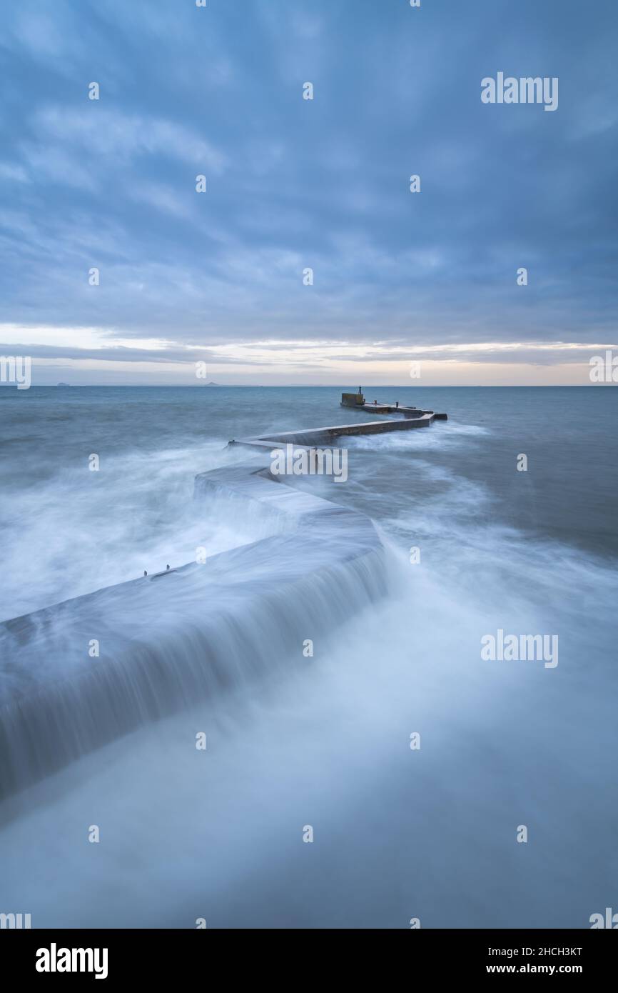 Waves crashing over the iconic zig-zag breakwater at St Monans harbour in the East Neuk of Fife, Scotland, UK. Stock Photo