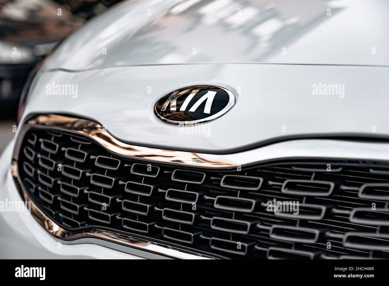 Textured grille with chrome trim and KIA logo on front of white car. Stock Photo