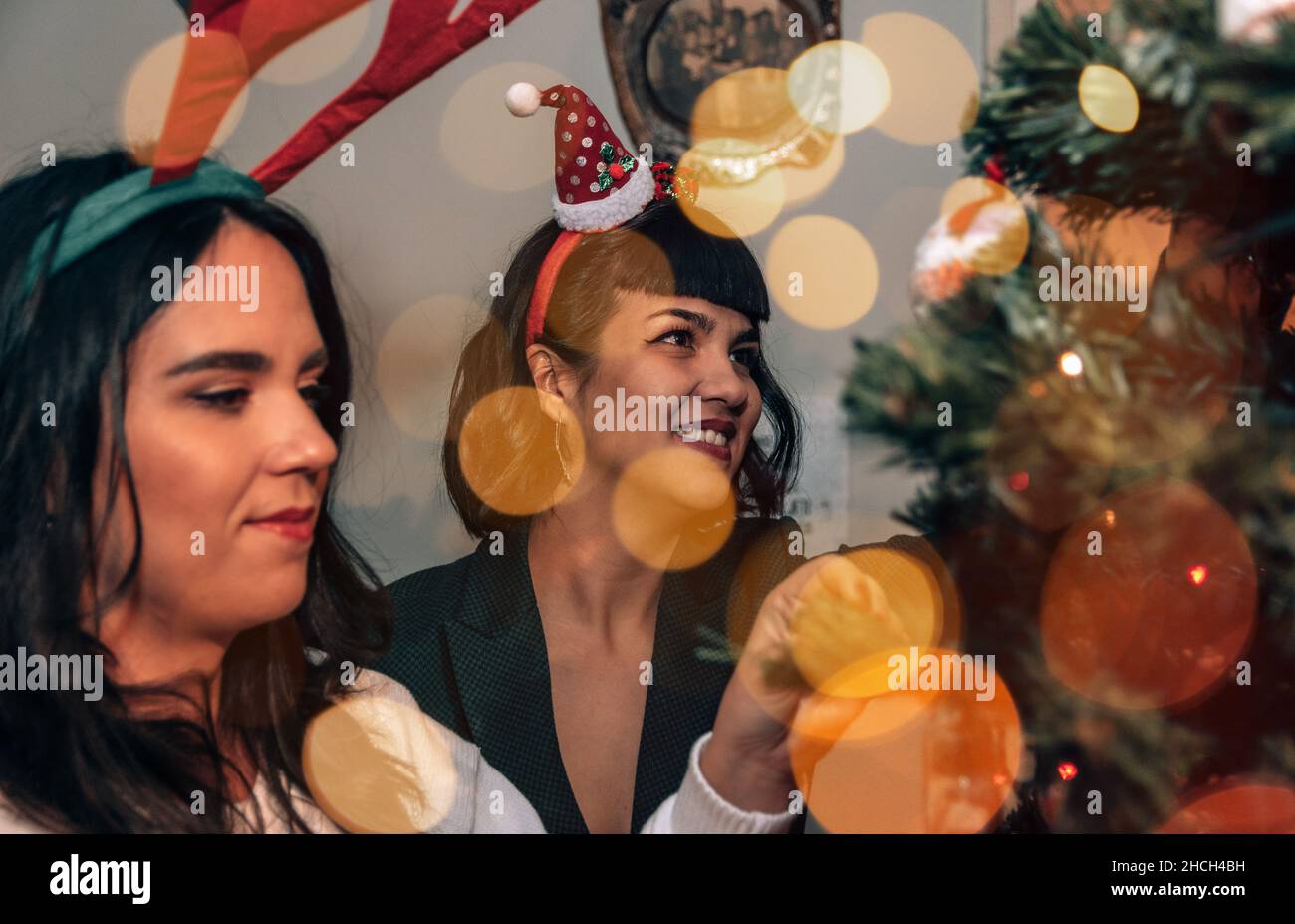 Two beautiful happy young women decorating christmas tree on christmas