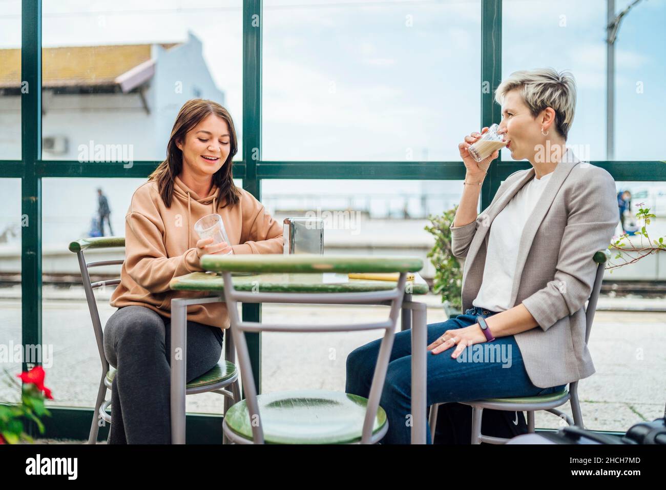 Two travelling women with luggage drinking coffee at train station, Portugal Stock Photo
