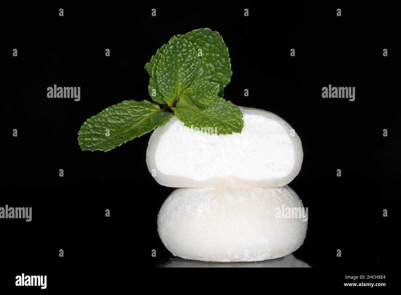 Halved mochi (cake made from glutinous ice cream flour) and mint, filled with coconut ice cream, studio photography with a black background Stock Photo