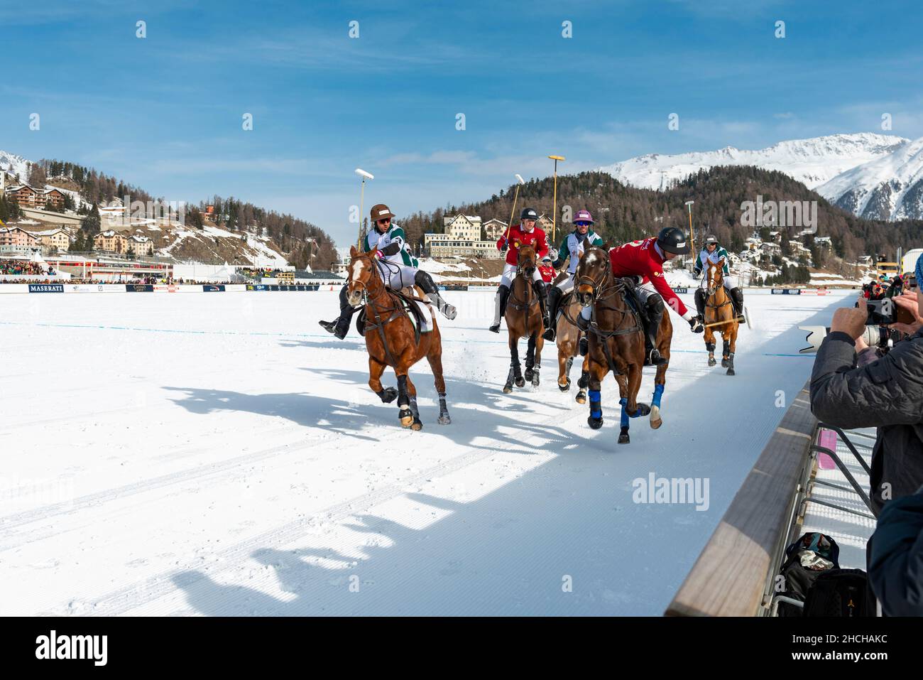 Players from Team St. Moritz (red) and players from Team Azerbaijan Land of Fire (white) fight for the ball on the rail, 36th Snow Polo World Cup St. Stock Photo