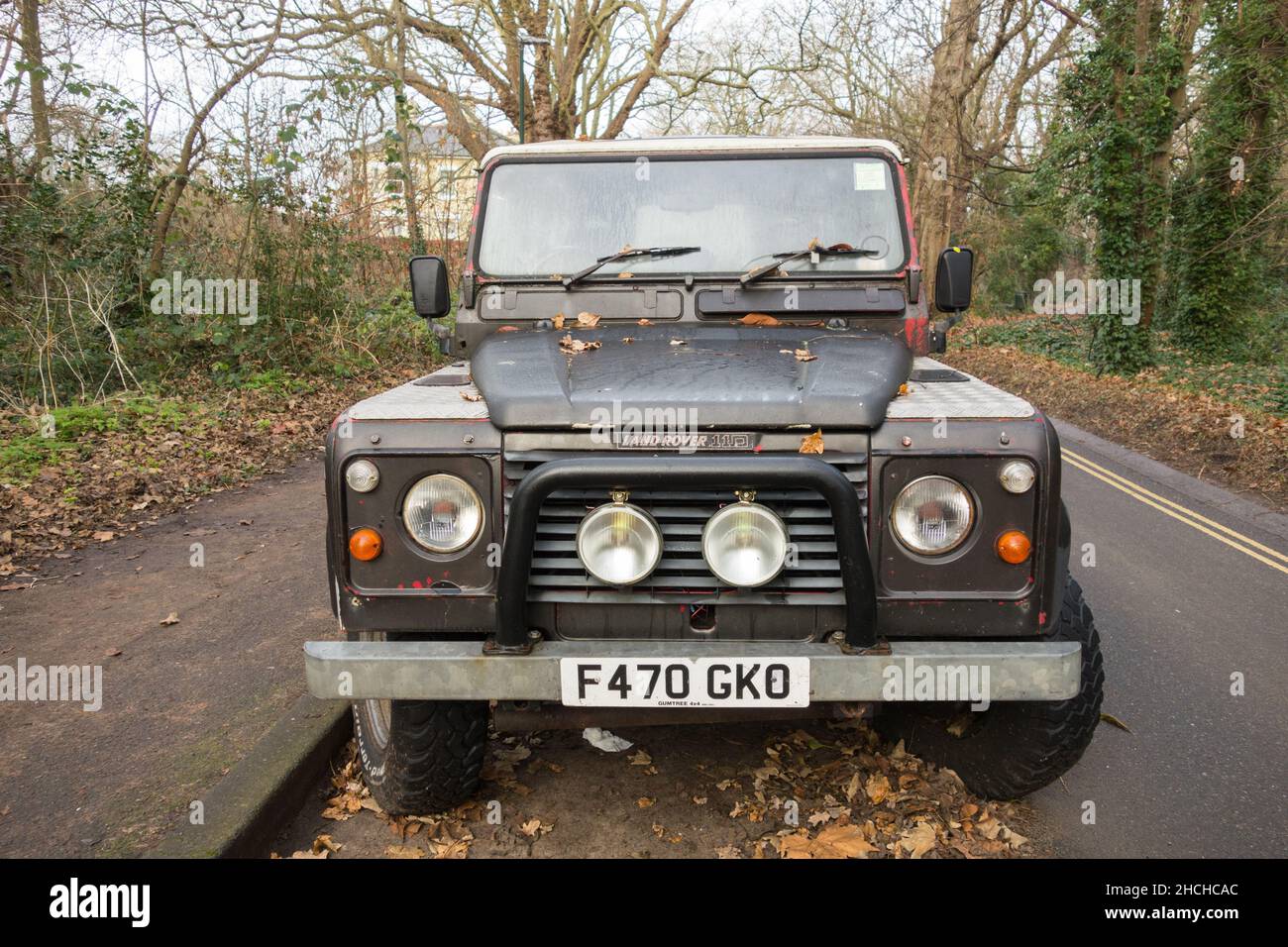A grey-green Land Rover Defender 110 parked on a quiet road Stock Photo