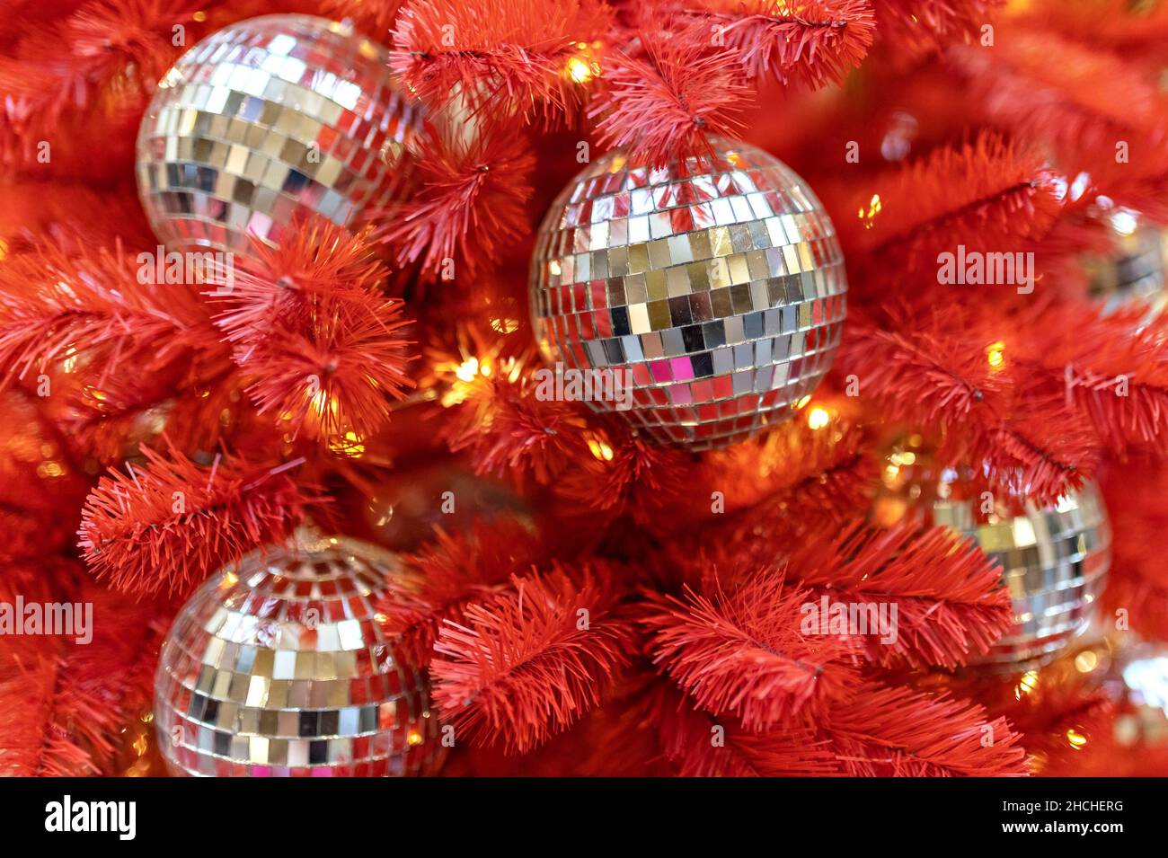 A red Christmas tree decorated with silver toys . Background with bokeh. New Year. Stock Photo