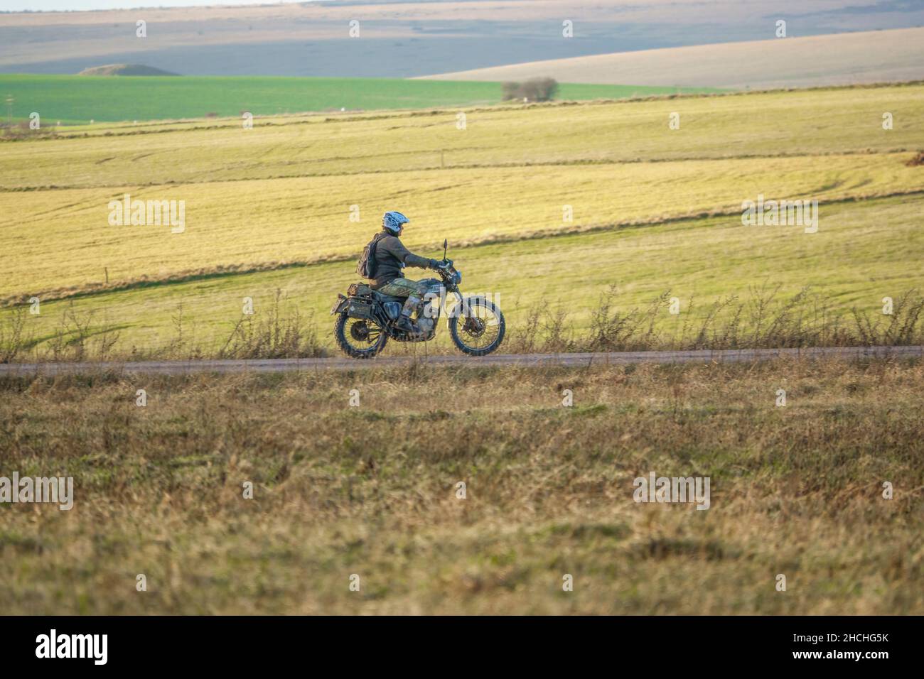a motor cyclist (biker) riding his offroad motorbike along a stone